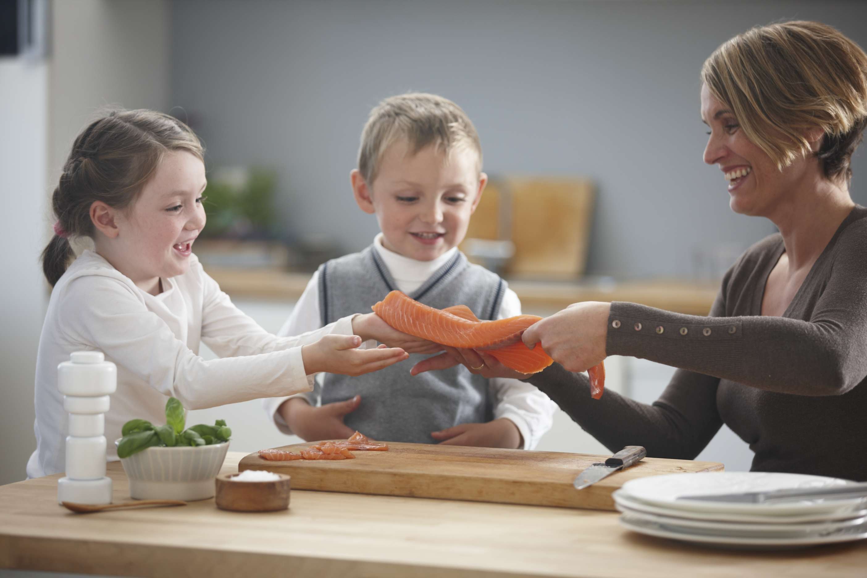 Barn på kjøkkenet med helfilet av laks
