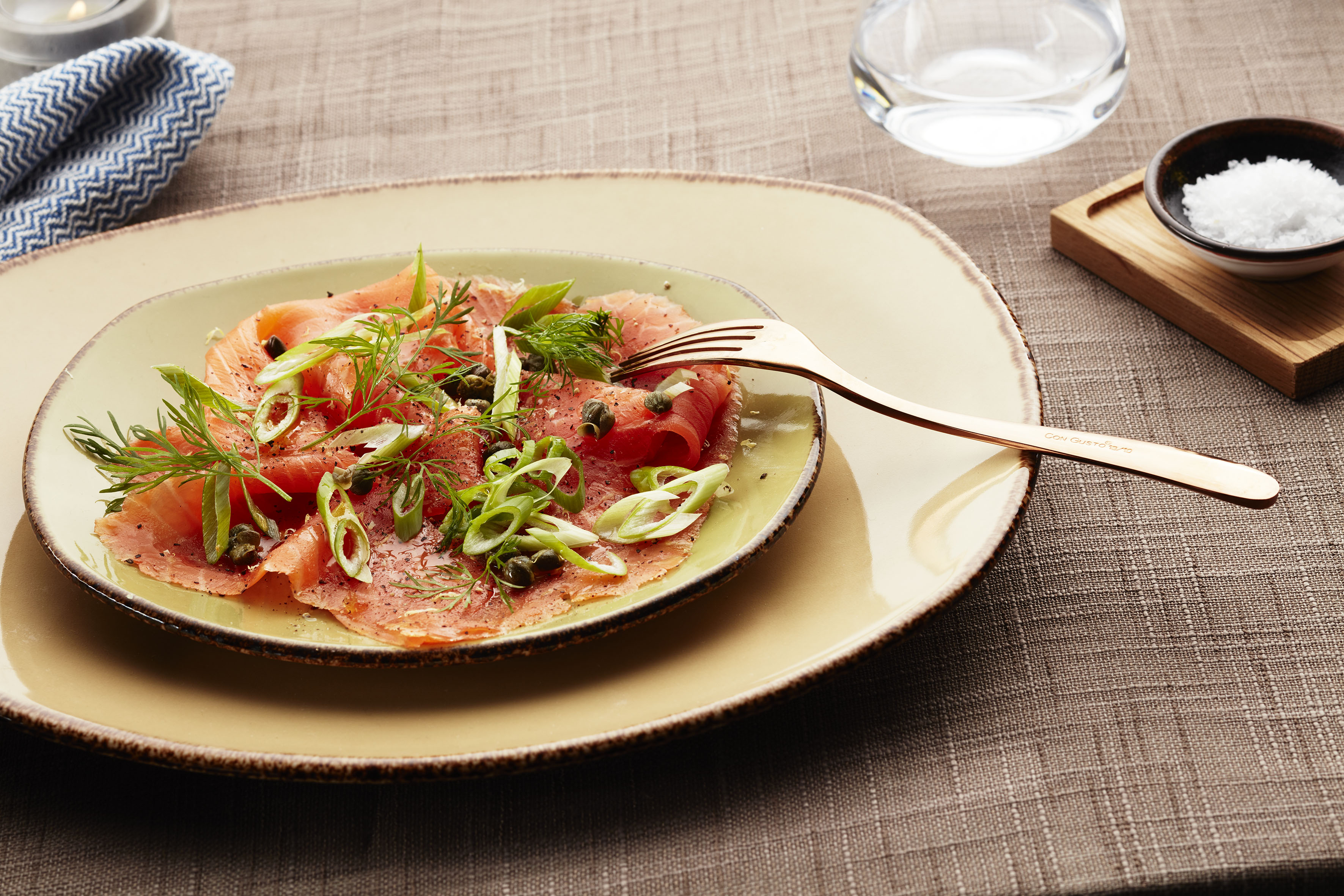 Carpaccio av røkt ørret servert med vårløk og sitron